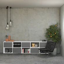 a living room with a book shelf, chair and potted plant