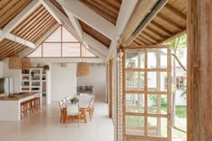 an open kitchen and dining room area with wooden beams on the ceiling, white walls and floor