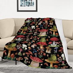 a black blanket with mushrooms on it is sitting in front of a couch and chair