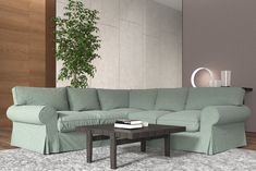 a living room with a sectional couch and coffee table in front of a plant on the wall