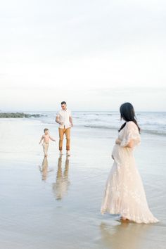 a man, woman and child are walking on the beach with their feet in the water