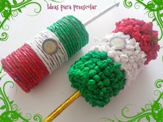 two red, white and green pom - poms on a stick