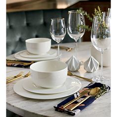 the table is set with white dishes and gold cutlery, silver utensils