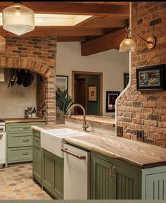 a kitchen with green and white cabinets, an island counter top and brick wall in the background