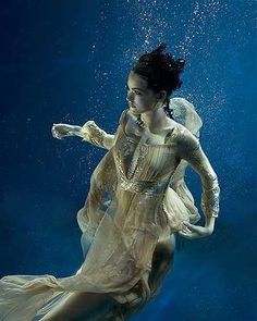 a woman in a dress floating under water