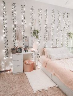 a bedroom with white lights on the wall and pink bedding in front of it