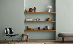 a living room with green walls and shelves filled with books, vases and other items