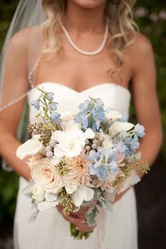 a bride holding a bouquet of white and blue flowers