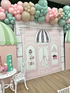 a room with balloons, tables and chairs in front of a wall that has a cake shop on it