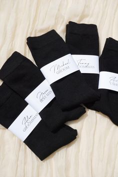 five pairs of black socks with white labels on them sitting on top of a bed