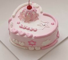 a pink birthday cake with white frosting and decorations