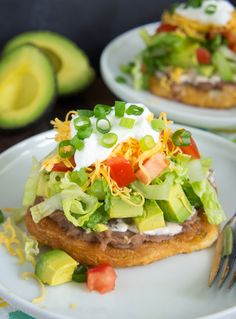 two white plates with food on them and one has an avocado in the background