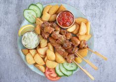 a plate with meat and vegetables on skewers next to dipping sauce in a bowl