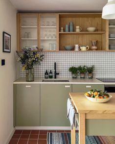 a bowl of fruit is sitting on the counter top in this modern kitchen with wood cabinets and tile backsplash