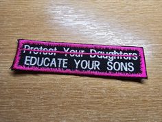 a pink and black patch that says, protect your daughters education your sons on it