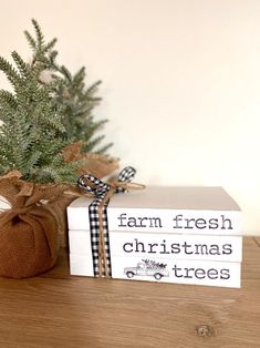 a small christmas tree sitting on top of a wooden table next to two boxes that say farm fresh christmas trees