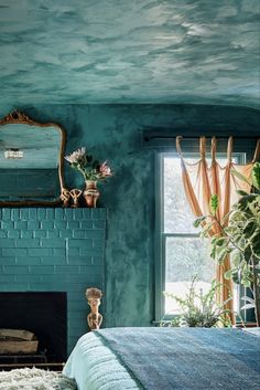 a bedroom with green painted walls and a blue bed in front of a fire place