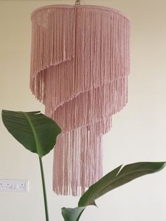 a pink chandelier hanging from the ceiling next to a green plant