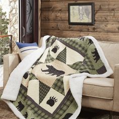 a couch with a blanket on it in front of a wooden wall and window sill