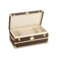 an open brown suitcase sitting on top of a white floor covered in gold trimmings