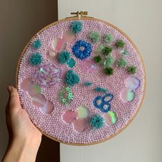 someone is holding up a hand made embroidery project with beads and pom - poms