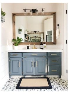 a bathroom with a large mirror and blue cabinetry in the center, along with a rug on the floor