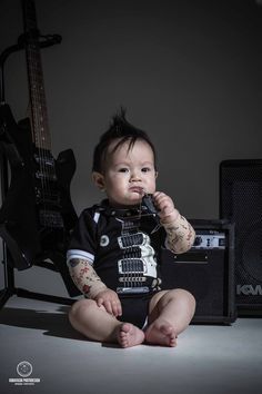 a baby sitting on the floor with a guitar in front of him and his mouth open