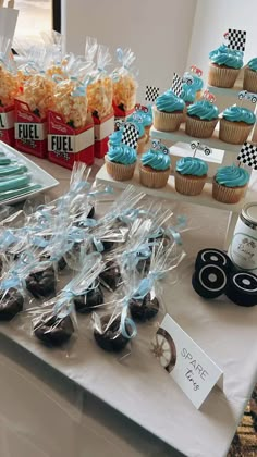 a table topped with lots of cupcakes covered in blue frosting and candy