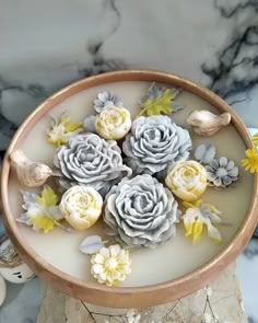 some flowers are sitting in a bowl on a marble table with white and yellow decorations