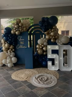 balloons and numbers are on display at the entrance to a 50th birthday party in blue, gold and white