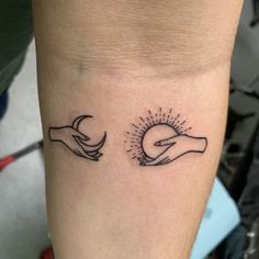 two hands holding each other with the sun and moon above them tattoo on both forearms