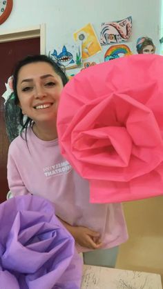 a woman is holding two large paper flowers