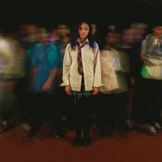 a woman standing in front of a group of people with blurry images behind her