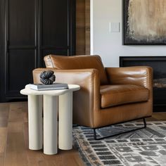 a living room with a chair, table and painting on the wall in it's corner