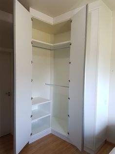 an empty closet with white walls and wooden floors