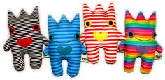 four stuffed animals are lined up in a row on a white background, one is wearing a striped shirt and the other has a heart