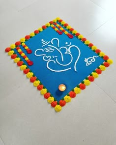 a blue square decorated with colorful pom poms and a lit candle on the floor