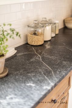 the kitchen counter is covered in black granite and has two jars with plants on it