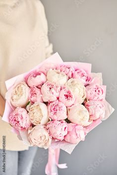 a woman holding a bouquet of pink and white peonies in her left hand