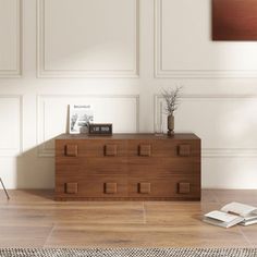 an empty room with a wooden dresser and books on the floor in front of it