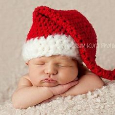 a newborn baby wearing a red and white crocheted santa hat