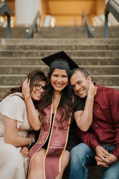 two women and a man are posing for a photo in graduation caps and gowns