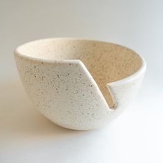 a white bowl with a curved handle on the side and small speckles in it