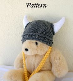 a teddy bear wearing a knitted viking hat and holding a yellow rope with the word pattern on it