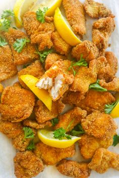 fried chicken with lemons and parsley on a white paper towel, ready to be eaten