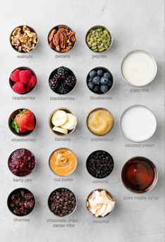 an overhead view of different types of fruit and nuts in small bowls on a table