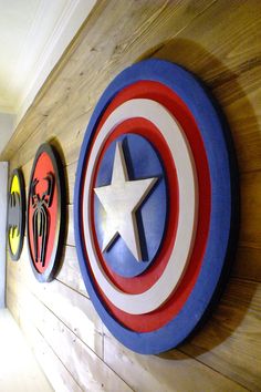 the captain's shield is mounted on the wall next to other superheros and spider - man emblems