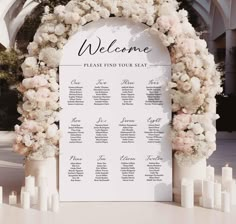 a welcome sign with flowers and candles on the side for guests to sit down at