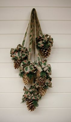 two pine cones are hanging on the wall next to each other with ribbons around them