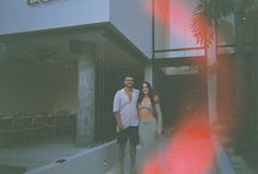 a man and woman standing in front of a building with a red light on it